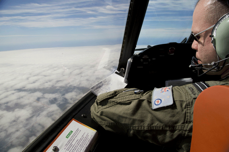 Flight Lieutenant Jayson Nichols looks out of the cockpit of a Royal Australian Air Force AP-3C Orion aircraft over cloud while searching for the missing Malaysian Airlines flight MH370 over the southern Indian Ocean on March 27.  Thunderstorms and gale-force winds grounded the international air search for wreckage from Flight MH370, frustrating the effort yet again as Thailand reported a satellite sighting of hundreds of floating objects.  (AFP)