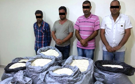 The four drug smugglers arrested by Dubai Police along with sacks of the banned painkiller 'Kaptagon' pills.