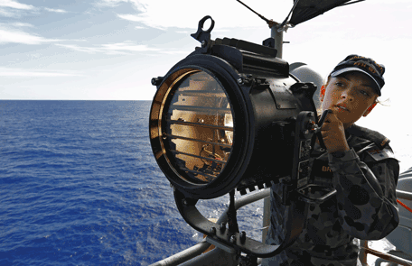 This handout photo taken on April 7, 2014 and released on April 9, 2014 by Australian Defence shows Communications and Information Systems, Seaman Georgina Brooks signaling HMAS Success for a replishement at sea (RAS) on the starboard bridge wing of HMAS Perth while searching for missing Malaysia Airlines flight MH370 in the southern Indian Ocean.  Two fresh signals have been picked up Australian ship Ocean Shield in the search for missing Malaysian flight MH370, raising hopes that wreckage will be found within days even as black box batteries start to expire.  (AFP)