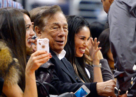 In this photo taken on Friday, Oct. 25, 2013, Los Angeles Clippers owner Donald Sterling, (centre) and V. Stiviano (right) watch the Clippers play the Sacramento Kings during the first half of an NBA basketball game, in Los Angeles. (AP)