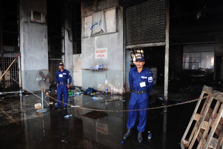 Pakistani security personnel stand guard behind a cordon at the damaged premises of a cold-storage cargo facility at the Jinnah International Airport in Karachi. (AFP)
