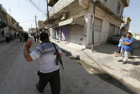 An Iraqi man carries his weapon as he walks along a street in the town of Bartala, on June 15, 2012, east of the northern city of Mosul, as some Iraqi police and security remain in the town to protect the local churches and community.  The exiled governor of Mosul, Iraq's second city which was seized by fighters last week, has called for US and Turkish air strikes against the militants.  (AFP)