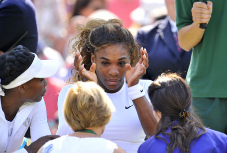 Serena Williams (centre) sits next to her partner Venus Williams after being taken ill during their women's doubles second round match against Germany's Kristina Barrois and Switzerland's Stefanie Voegele on day eight of the 2014 Wimbledon Championships at The All England Tennis Club in Wimbledon, London, on July 1, 2014. (AFP)