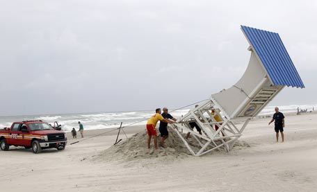 Lifeguards and firefighters voluntarily set down a lifeguard stand, rather than have it damaged from the coming of Hurricane Arthur, at Atlantic Beach. (AP)