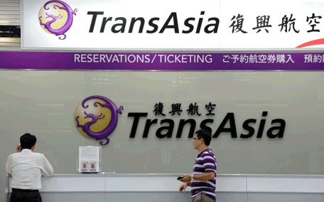 Local journalists wait in front of a TransAsia reservations desk at the Sungshan airport in Taipei on July 23, 2014. More than 40 people were killed in a plane crash in Taiwan, officials said, with local television reporting the flight had smashed into two houses after an aborted landing. Authorities said Taiwanese airline TransAsia Airways flight GE222, with 58 on board, crashed near Magong airport on the outlying Penghu island after having requested a second attempt to land.  (AFP)