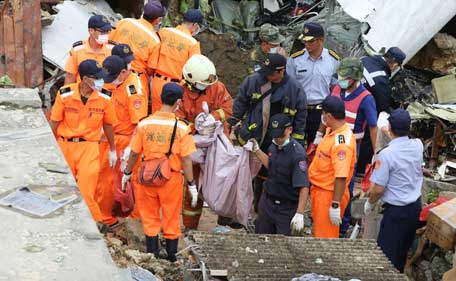 Rescue workers survey the wreckage of TransAsia Airways Flight GE222 which crashed on the Taiwanese island of Penghu Thursday, July 24, 2014. The plane attempting to land in stormy weather crashed on the island late Wednesday, killing more than 40 people and wrecking houses and cars on the ground. (AP)