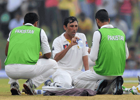 Pakistan cricketer Younis Khan (C) takes a water break during the first day of the opening Test match between Sri Lanka and Pakistan at the Galle International Cricket Stadium in Galle on August 6, 2014. AFP