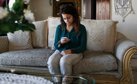 Farah Baker, 16, uses her phone to tweet in her family's home in Gaza City, August 10, 2014. As bombs explode in Gaza, Palestinian teenager Farah Baker grabs her smartphone or laptop before ducking for cover to tap out tweets that capture the drama of the tumult and fear around her. The 16-year-old's prolific posts on Twitter have made her a social media sensation through the month-old conflict. Once a little known high school athlete, Baker's following on the Web site has jumped from a mere 800 to a whopping 166,000. Picture taken August 10, 2014. REUTERS/