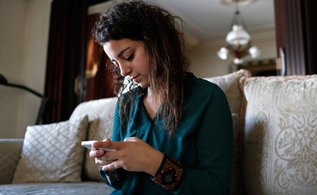 Farah Baker, 16, uses her phone to tweet in her family's home in Gaza City, August 10, 2014. As bombs explode in Gaza, Palestinian teenager Farah Baker grabs her smartphone or laptop before ducking for cover to tap out tweets that capture the drama of the tumult and fear around her. The 16-year-old's prolific posts on Twitter have made her a social media sensation through the month-old conflict. Once a little known high school athlete, Baker's following on the Web site has jumped from a mere 800 to a whopping 166,000. Picture taken August 10, 2014.  (REUTERS)
