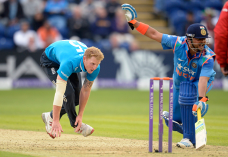 England's Ben Stokes jumps off the ground after attempting to stop the ball as India's Suresh Raina holds his hand up during the second one-day international cricket match at the SWALEC stadium in Cardiff August 27, 2014.  REUTERS