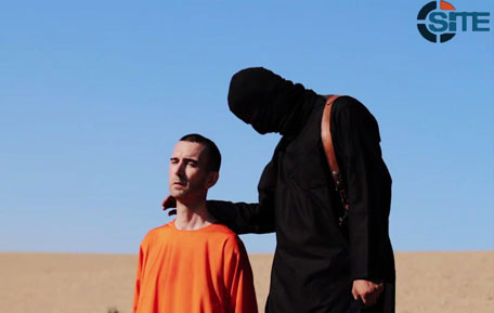 An image grab taken from a video released by 'Daesh' and identified by private terrorism monitor SITE Intelligence Group on September 13, 2014 purportedly shows British aid worker David Haines dressed in orange and on his knees in a desert landscape speaking to the camera before being beheaded by a masked militant (R). (AFP)