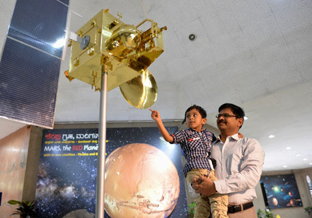 A father and son look at a scale model of India's Mars Orbiter spacecraft  at the Nehru Planetarium as a special preview on the Mars Orbiter Mission, in Bangalore on September 23, 2014. (AFP)