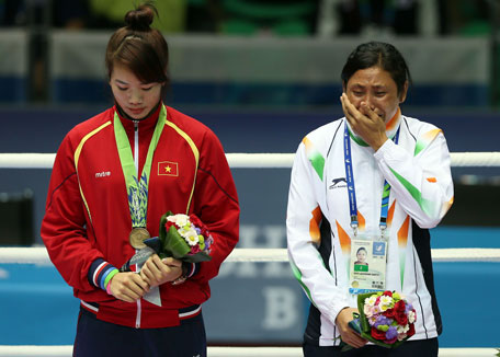 Bronze medalist India's Sarita Devi (right) cries after she refused her bronze medal as bronze medalist Vietnam's Thi Duyenin Luu stands beside in the medal ceremony of the women's lightweight (57-60kg) boxing event during the 2014 Asian Games at Seonhak gymnasium in Incheon on October 1, 2014. (AFP)