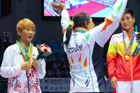Bronze medalist India's Sarita Devi (centre) waves after she presented her bronze medal to silver medalist South Korea's Park Jina in the medal ceremony of the women's lightweight (57-60kg) boxing event during the 2014 Asian Games at Seonhak gymnasium in Incheon on October 1, 2014. (AFP)