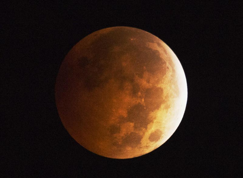 The moon appears to be to have an orange-red hue as the earth's shadow covers the moon during a total lunar eclipse, in Griffith Park in Los Angeles, California October 8, 2014. A total lunar eclipse is sometimes called a blood moon because of the red color that is cast upon it by light refracting in Earth's atmosphere.  (AFP)