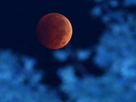 The Earth's shadow is cast over the moon during a total lunar eclipse over Milwaukee on Wednesday, Oct 8, 2014.  The red hue results from sunlight scattering off Earth's atmosphere, in what is known as a "blood moon." (AP)