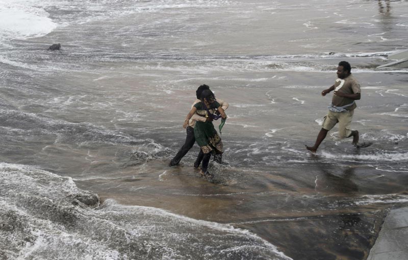 A man, right, rushes to help as another rescues a woman who fell due to strong tidal waves on the Bay of Bengal coast at Gopalpur, Orissa, about 285 km north east of Visakhapatnam, India, Sunday, October 12, 2014. (AP)