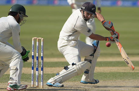 New Zealand batsman BJ Watling (right) is watched by Pakistan wicketkeeper Sarfraz Ahmed as he plays a shot during the second day of the second Test match between Pakistan and New Zealand at Dubai International Stadium in Dubai on November 18, 2014. (AFP)