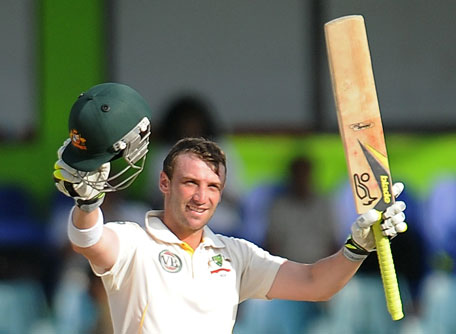 Australian batsman Phillip Hughes raises his bat and helmet in celebration after scoring a century (100 runs) during the fourth day of the third and final Test match between Australia and Sri Lanka at The Sinhalese Sports Club (SSC) Ground in Colombo. (AFP)