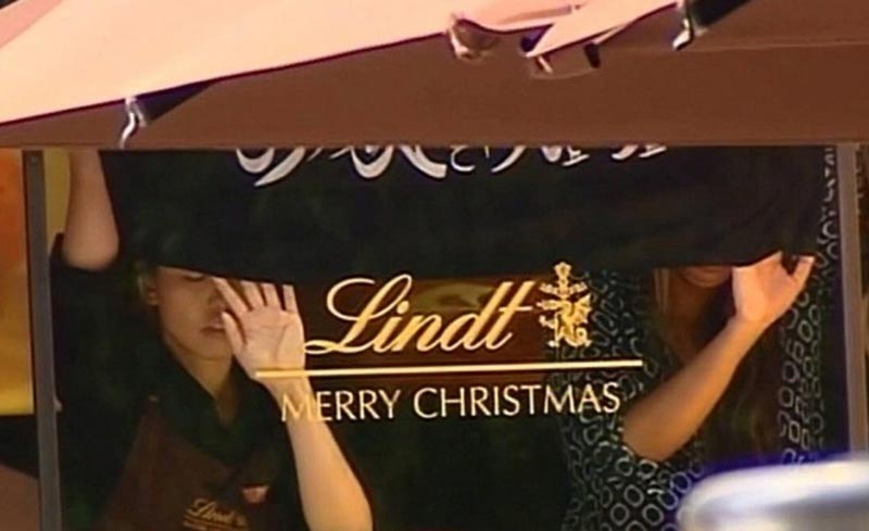 This screengrab taken from the Australian Channel Seven broadcast shows presumed hostages holding up a flag with Arabic writing inside a cafe in the central business district of Sydney on December 15, 2014. (AFP)
