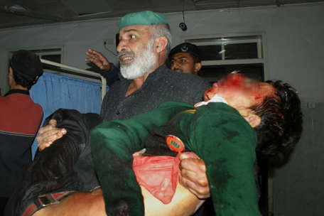 A Pakistani man carries an injured student at a hospital following an attack by Taliban gunmen on a school in Peshawar on December 16, 2014. Taliban insurgents killed at least 130 people, most of them children, after storming an army-run school in Pakistan December 16 in one of the country's bloodiest attacks in recent years. AFP