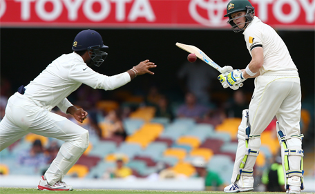 Australian batsman Steven Smith watches the ball as Indian fielder Cheteshwar Pujara looks to catch it during play on day two of the second cricket Test against India in Brisbane, Australia, Thursday, December 18, 2014. (AP)