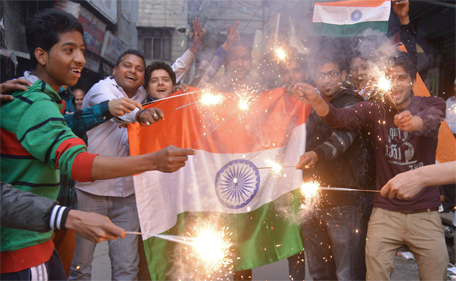 Indian fans pose with their national flags and hold sparklers as they celebrate after India won the 2015 Cricket World Cup's cricket match against Pakistan, in Amritsar on February 15, 2015. (AFP)