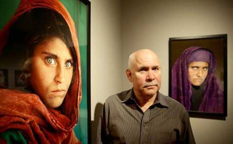 US photographer Steve McCurry poses next to his photos of 'Afghan Girl' Sharbat Gula at an exhibition of his work in Hamburg, Germany in June 2013. (AFP file)