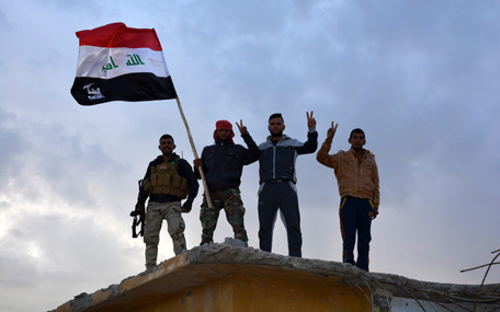 Iraqi government forces and allied militias gesture as they hold the national flag in the northern part of Diyala province, bordering Salaheddin province, as they take part in an assault to retake the city of Tikrit from Daesh. (AFP)