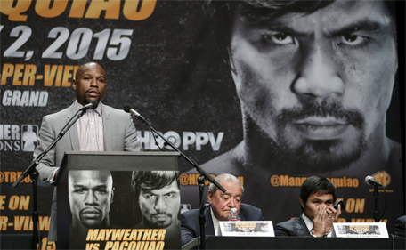 Floyd Mayweather Jr. (left) speaks as Manny Pacquiao (right) speaks into his phone while sitting next to promoter Bob Arum during a news conference, Wednesday, March 11, 2015, in Los Angeles. (AP)