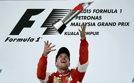 Ferrari's German driver Sebastian Vettel throws the trophy as he celebrates on the podium after winning the Formula One Malaysian Grand Prix in Sepang on March 29, 2015.  (AFP)