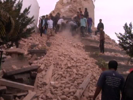 In this image from AP video people search in a buildings rubble in Kathmandu, Nepal after a strong earthquake hit the area Saturday April 25, 2015. A strong magnitude-7.9 earthquake shook Nepal's capital and the densely populated Kathmandu Valley before noon Saturday, causing extensive damage with toppled walls and collapsed buildings, officials said. (AP video via AP)