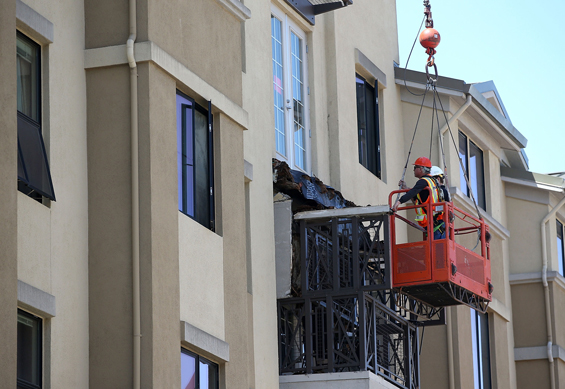 Workers inspect a balcony that collapsed at an apartment building near UC Berkeley on June 16, 2015 in Berkeley, California. (AP)