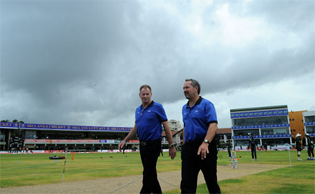 Australian umpire Paul Reiffel (left) and England umpire Richard Illingworth walk out to inspect the playing surface after rain showers delayed play during the second day of the opening Test match between Sri Lanka and Pakistan at The Galle International Cricket Stadium in Galle on June 18, 2015. (AFP)