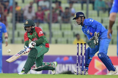Bangladesh cricketer Mushfiqur Rahim (L) plays a shot as Indian cricket captain  Mahendra Singh Dhoni (R) looks on during the first one day international (ODI) cricket match between Bangladesh and India at The Sher-e-Bangla National Cricket Stadium in Dhaka on June 18, 2015. AFP