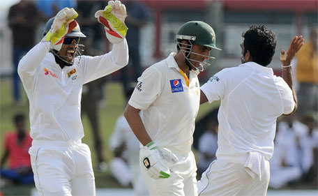 Sri Lankan bowler Dilruwan Perera (right) and wicketkeeper Dinesh Chandimal (left) celebrate after the dismissal of Pakistan batsman Younis Khan during the third day of the opening Test cricket match between Sri Lanka and Pakistan at the Galle International Cricket Stadium in Galle on June 19, 2015. (AFP)