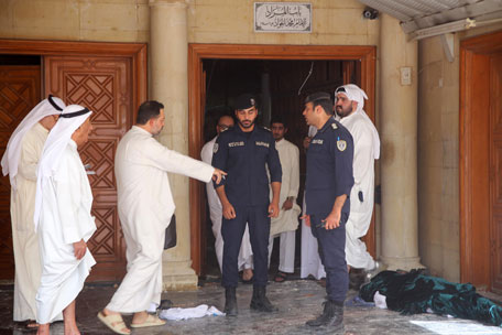 Kuwaiti security forces stand next to a body wrapped in shrouds as they inspect the site of a suicide bombing that targeted the mosque during Friday prayers on June 26, 2015, in Kuwait City. (AFP)