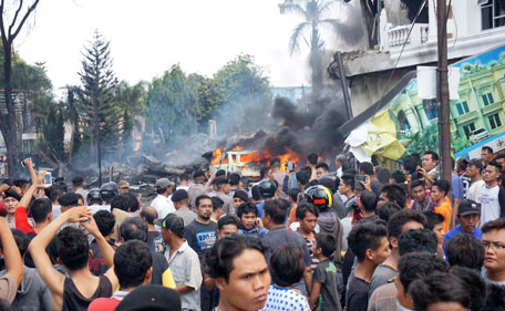 Residents gather next to the crash site of a military Hercules plane in Medan, North Sumatra province on June 30, 2015. An Indonesian military transport plane crashed shortly after take off in the city, an official said, with the plane exploding in a ball of flames. (AFP)