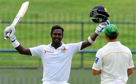 Sri Lankan cricket captain Angelo Mathews raises his bat and helmet in celebration after scoring a century during the fourth day of the third and final Test cricket match between Sri Lanka and Pakistan at the Pallekele International Cricket Stadium in Pallekele on July 6, 2015. (AFP)