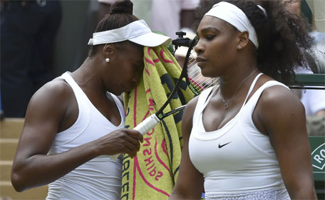 Venus Williams wipes her face as Serena Williams looks on during their match at the Wimbledon Tennis Championships in London, July 6, 2015. (Reuters)