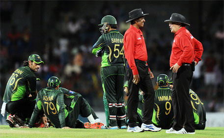 Pakistani cricketers sit on the ground after the game was disrupted due to stone hurling in spectator stands during the third One Day International match between Sri Lanka and Pakistan at the R. Premadasa International Cricket Stadium in Colombo on July 19, 2015.  (AFP)