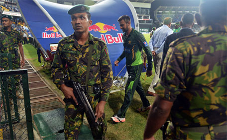 Pakistan's Shoaib Malik (cnetre) walks past security forces as he and teammates walk off the field after clashes between supporters of both sides during the third one day international between Sri Lanka and Pakistan at the R Premadasa International Cricket Stadium in Colombo on July 19, 2015. (AFP)