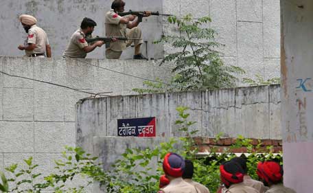 Indian policemen take their positions as their colleagues watch next to a police station during a gunfight at Dinanagar town in Gurdaspur district of Punjab, India, July 27, 2015. (Reuters)