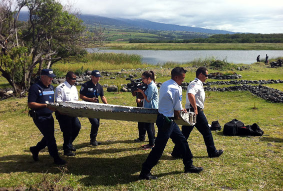 Police carry a piece of debris from an unidentified aircraft found in the coastal area of Saint-Andre de la Reunion, in the east of the French Indian Ocean island of La Reunion. (AFP)