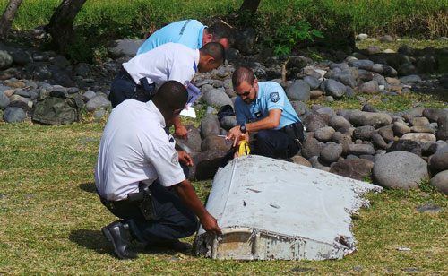 French gendarmes and police inspect a large piece of plane debris which was found on the beach in Saint-Andre, on the French Indian Ocean island of La Reunion, in this picture taken July 29, 2015. Investigators in France have ascertained that the barnacle-covered debris, a 2-2.5 metre (6.5-8 feet) wing surface known as a flaperon, belonged to Malaysia Airlines flight MH370 just days after Malaysia identified it as being part of the same model, a Boeing 777. Picture taken July 29, 2015. (REUTERS)
