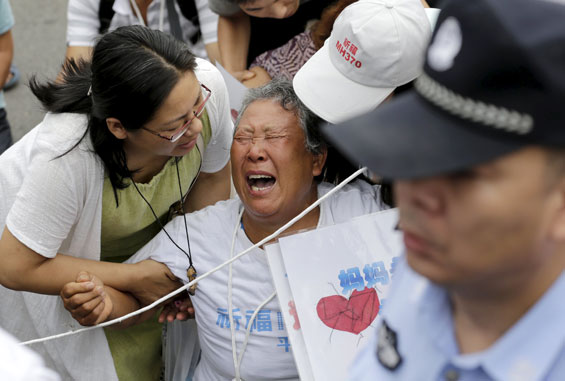Wang Zhuncai, whose daughter was aboard Malaysia Airlines flight MH370, cries as she and other family members kneel down in front of media ahead of a briefing given by Malaysia Airlines, in Beijing. (Reuters)