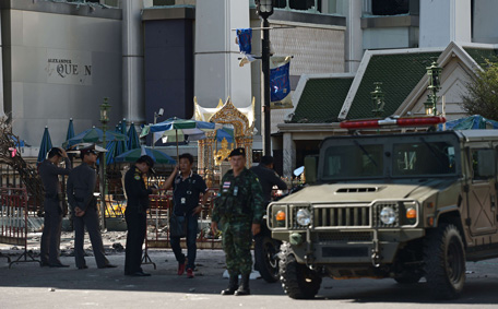 Police officers and soldiers stand at the cordoned-off site of a bomb blast outside the popular Erawan shrine (background) in the heart of Bangkok's tourist and commercial centre on August 18, 2015.  The death toll from a bomb blast in the Thai capital rose to 21 on August 18 with 123 wounded, police said, with seven tourists from China, Hong Kong, Malaysia and Singapore among those killed in the attack.  (AFP)