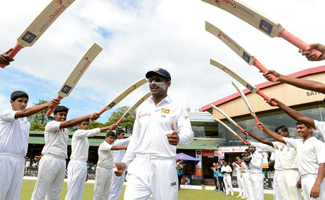 Sri Lankan cricketer Kumar Sangakkara (centre) walks through an 'archway of cricket bats' as he goes out to field during the opening day of their second Test match between Sri Lanka and India at the P. Sara Oval Cricket Stadium in Colombo on August 20, 2015. (AFP)