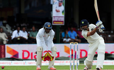 Indian cricket captain Virat Kohli (right) plays a shot as Sri Lankan wicketkeeper Dinesh Chandimal looks on during the opening day of their second test match between Sri Lanka and India at the P. Sara Oval Cricket Stadium in Colombo on August 20, 2015. (AFP)