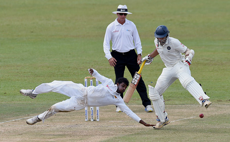Sri Lankan cricketer Tharindu Kaushal dives as he unsuccessfully attempts to stop the ball as Indian cricketer Naman Ojha (R) looks on during the second day of their third and final Test cricket match between Sri Lanka and India at the Sinhalese Sports Club (SSC) in Colombo on August 29, 2015.  (AFP)